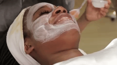 девушке наносят крем на лицо